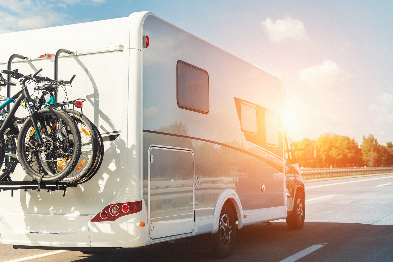 Camper bianco con portabici in autostrada al tramonto