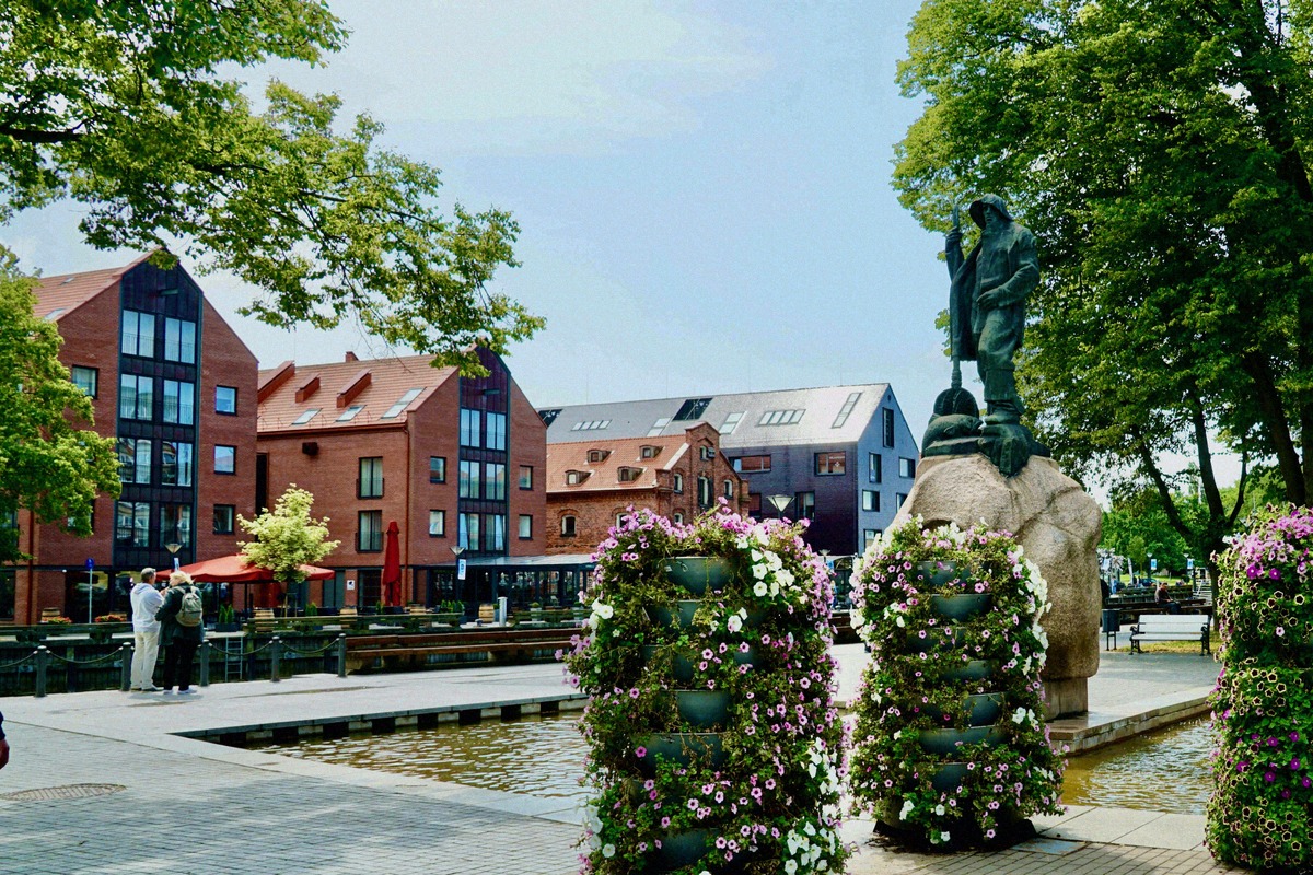 The Danė promenade in Klaipėda, with the fisherman sculpture and old warehouses.