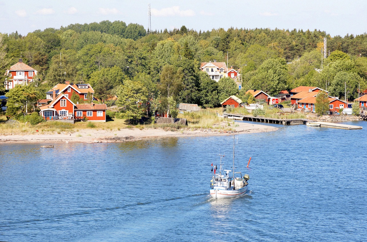 Fishing boat returning to Grisslehamn harbour, red wooden houses behind